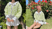 A young woman wearing a handmade, green and white checkered crochet sweater with frilled cuffs and collar. The image is divided into two sections: the left side shows her standing against a leafy background, showcasing the intricate crochet work of the sweater, while the right side captures her sitting on the grass near vibrant red roses, smiling and looking to the side. She pairs the sweater with a white pleated skirt and accessorizes with colorful rings and bracelets.